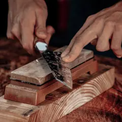 Manos afilando un cuchillo con una piedra de afilar. Aprende como afilar cuchillos con afilador para un corte perfecto.